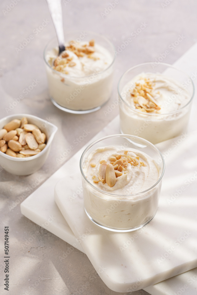 Creamy dairy yoghurt dessert with mascarpone, cream cheese and peanut butter in glasses on marble tray Creamy dairy yoghurt dessert with mascarpone, cream cheese and peanut butter in glasses on marble tray