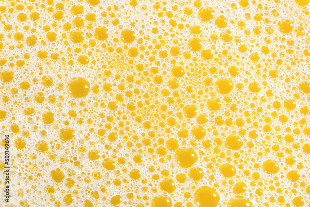 Closeup of orange juice foam, top view. Splash of fresh sweet orange, mango, fruit juice. Freeze motion of pouring orange juice . Closeup of orange juice foam, top view. Splash of fresh sweet orange, mango, fruit juice. Freeze motion of pouring orange juice .