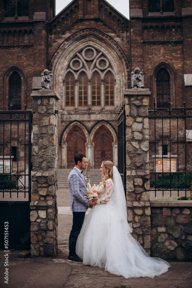 Obraz premium Beautiful newlywed couple standing near old christian church