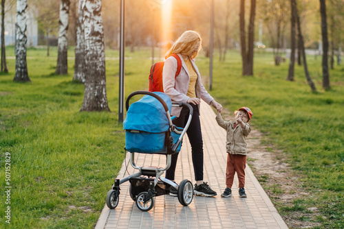 mom walks with stroller and toddler son in the park