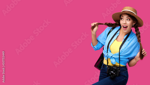 Tourism concept. Excited young caucasian woman tourist with photo camera, isolated on pink background. Female student hipster in casual clothes and straw hat