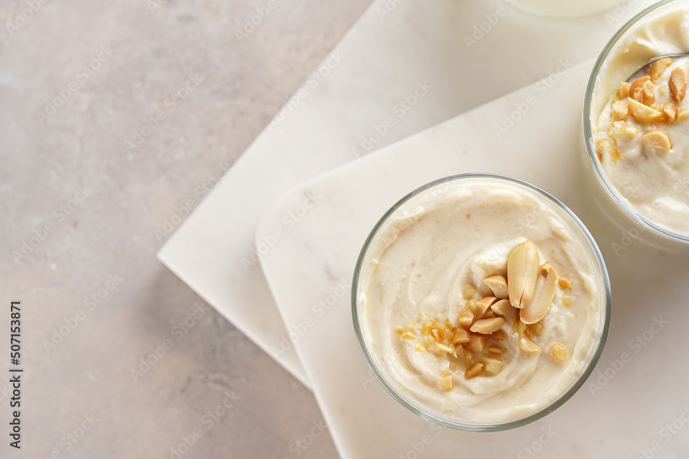 Creamy dairy yoghurt dessert with mascarpone, cream cheese and peanut butter in glasses on marble tray with a tea spoon Creamy dairy yoghurt dessert with mascarpone, cream cheese and peanut butter in glasses on marble tray with a tea spoon