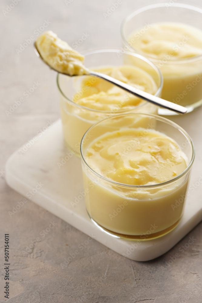 Creamy french vanilla pudding in glass on marble board on grey neutral background Creamy french vanilla pudding in glass on marble board on grey neutral background