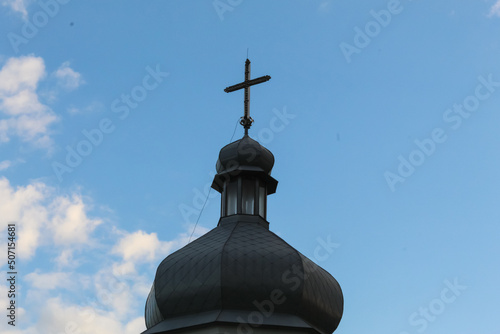 Dome and cross of a Christian church in the evening at sunset. Silhouette of a cross against the blue sky.