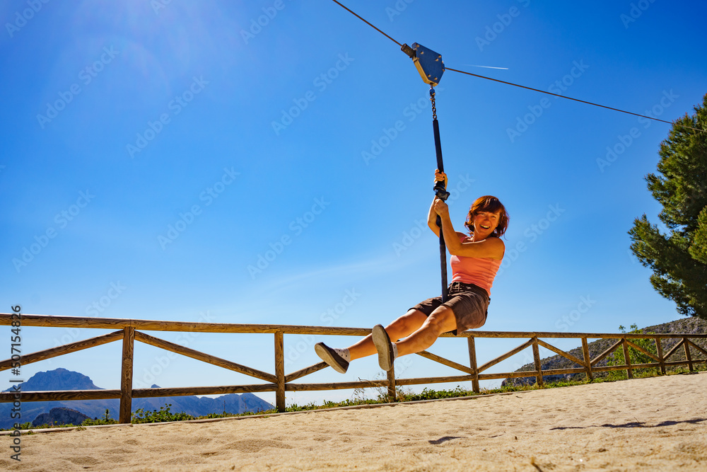 Fototapeta premium Adult woman having fun on zipline