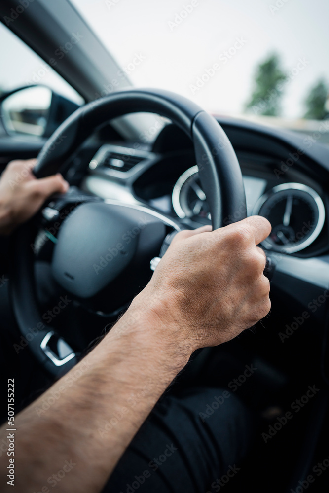 Male hands on a car's steering wheel