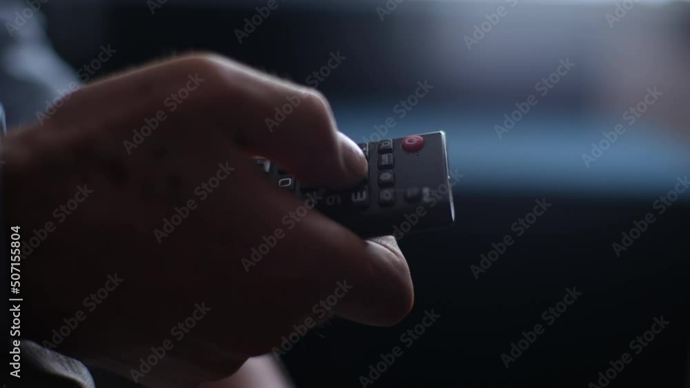 Close-up unrecognizable mature adult male hands holding TV remote control and switches TV channel. Closeup cropped shot of senior man flipping through TV channels with remote control, slow motion.