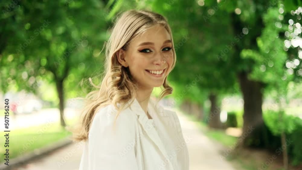 Portrait of attractive smiling woman while walking down the street in the city street and turn around. Beautiful woman looking at the camera outside. Portrait of attractive smiling woman while walking down the street in the city street and turn around. Beautiful woman looking at the camera outside.