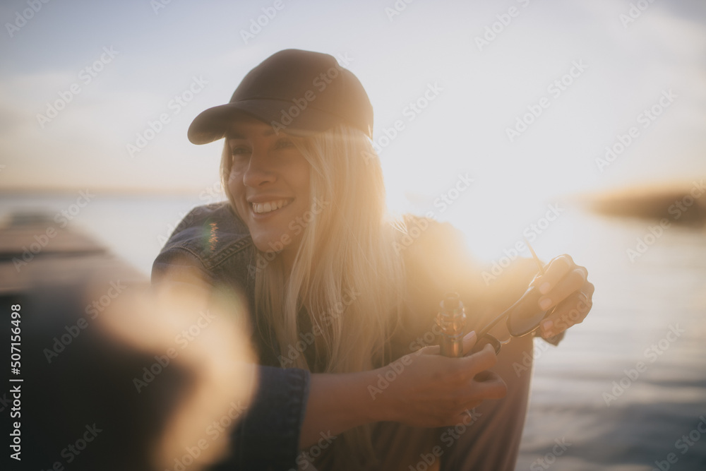 Uśmiechnięta dziewczyna na tle zachodzącego słońca nad jeziorem - obrazy, fototapety, plakaty 