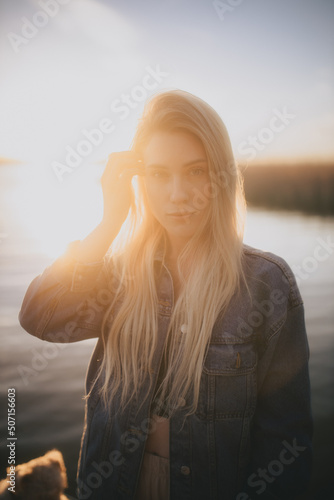 poważna dziewczyna na tle zachodzącego słońca nad jeziorem