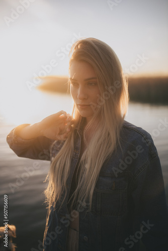 poważna dziewczyna na tle zachodzącego słońca nad jeziorem