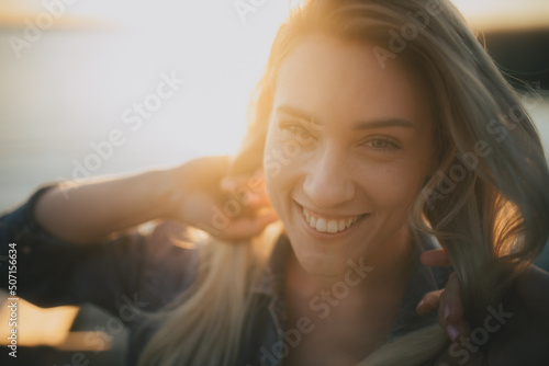 Uśmiechnięta dziewczyna na tle zachodzącego słońca nad jeziorem