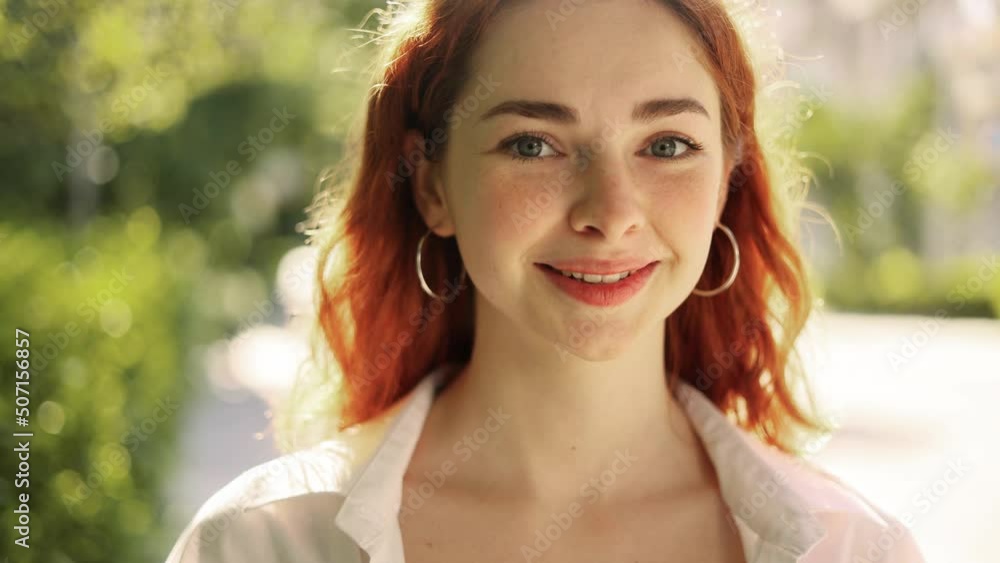 Portrait of attractive red haired woman while standing in the city street. Beautiful ginger woman looking at the camera outside. Portrait of attractive red haired woman while standing in the city street. Beautiful ginger woman looking at the camera outside.