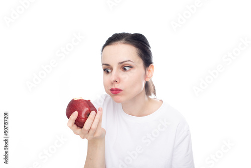 woman in white t-shirt eating red apple, white studio background