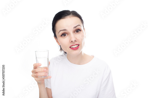 smiling woman in a white t-shirt holds a glass of water in her hand, white studio background
