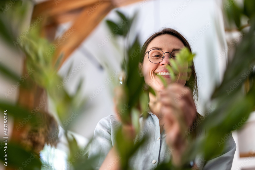 Obraz premium Young woman taking care of her houseplants