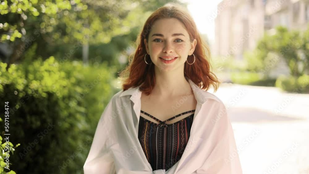 Portrait of attractive red haired woman while walking down the city street. Beautiful ginger woman looking ahead outside. Portrait of attractive red haired woman while walking down the city street. Beautiful ginger woman looking ahead outside.