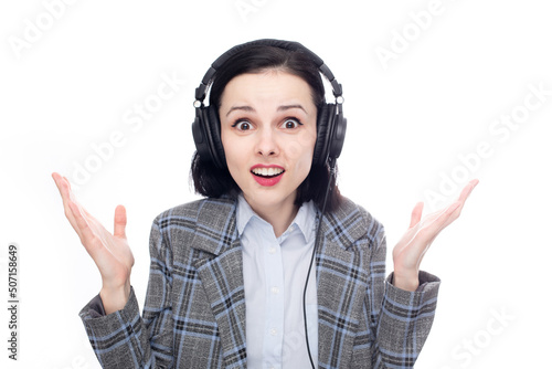 surprised woman in office suit listening to music in big full size headphones. High quality photo