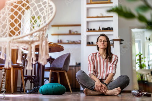 Quadro su tela Relaxed young woman sitting on the floor at home