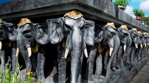 Statues of elephants in hats holding a concrete slab