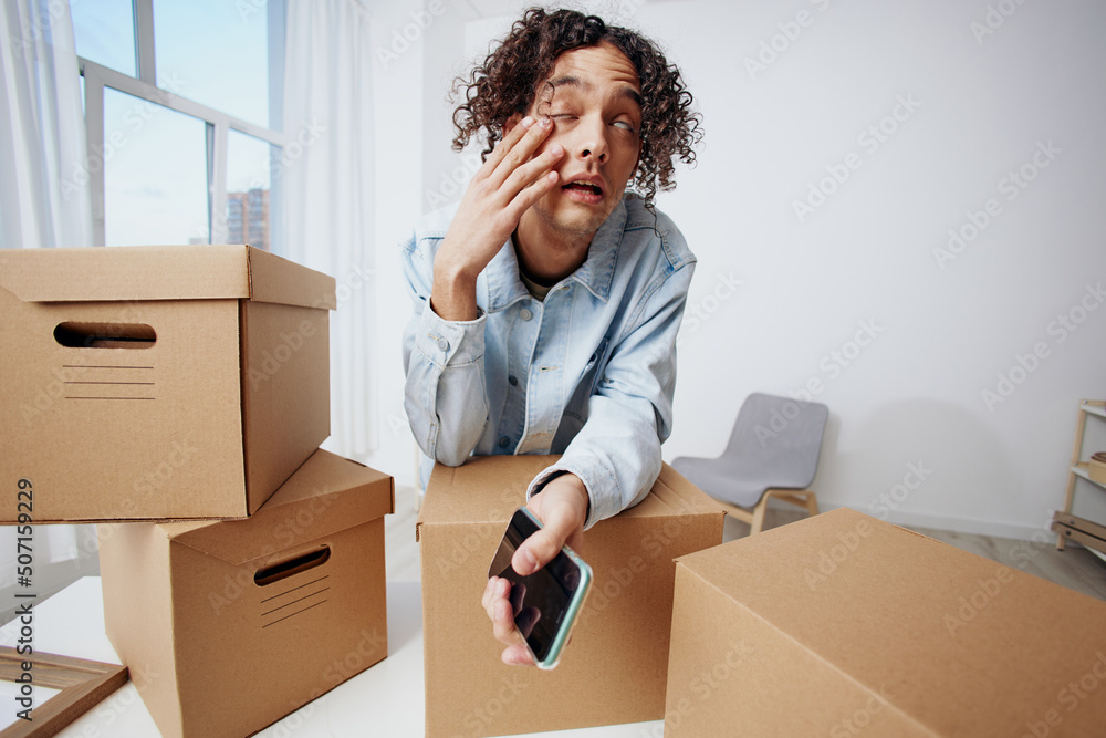 A young man unpacking things from boxes in the room interior A young man unpacking things from boxes in the room interior
