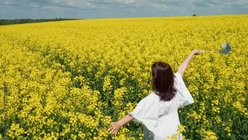 Ukraine, the Lviv region, the young pregnant girl cheerfully runs among rapeseed in a rapeseed field with a flag of Ukraine Ukraine, the Lviv region, the young pregnant girl cheerfully runs among rapeseed in a rapeseed field with a flag of Ukraine