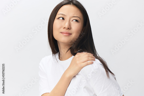 Suffering from neuralgia after sleeping in wrong position tanned beautiful young Asian woman touching painful shoulder isolated at white background. Injuries Poor health Illness concept. Cool offer © SHOTPRIME STUDIO