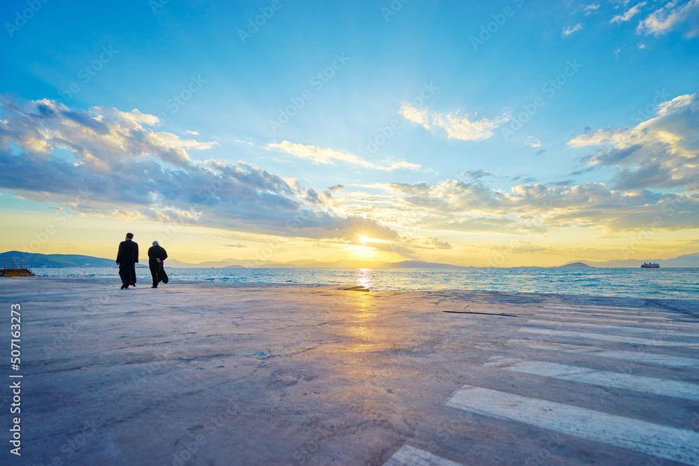 Two priests walking on the sea promenade with wonderful sunset view.