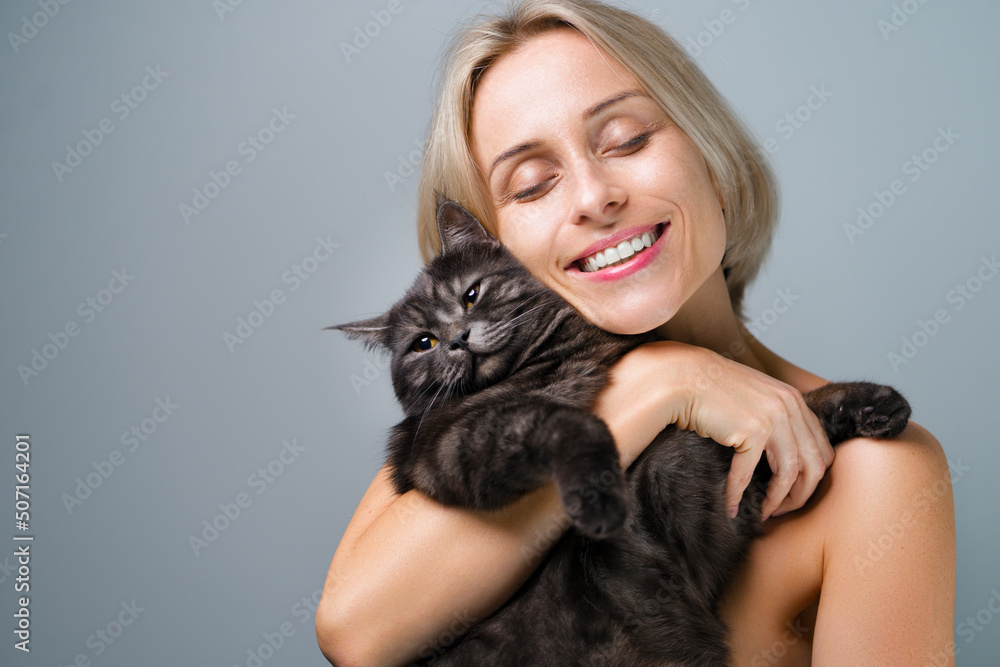 Studio portrait of young blode woman and her adorable black tabby cat.