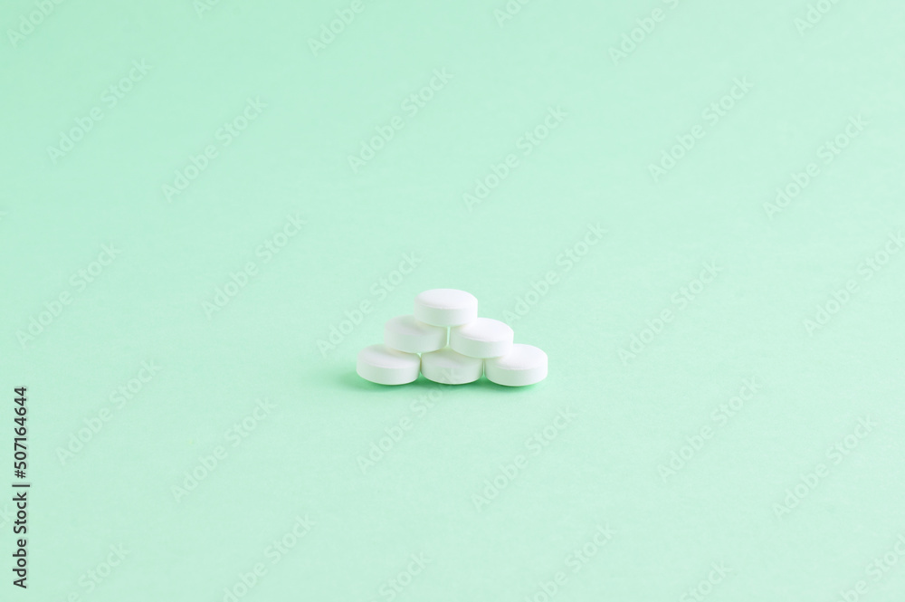 White pills of circular shape, stacked on light background.