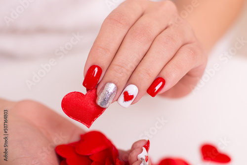 Beautiful female hands with red manicure nails, hearts design, on white background