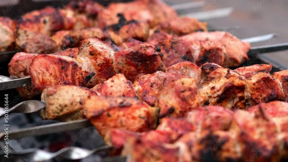 Close-up of grilling tasty dish on barbecue. Process of cooking yummy shashlik in nature. Delicious food on metal skewer in bbq. Time to picnic concept. Street food. Food festival. Pork at the stake Close-up of grilling tasty dish on barbecue. Process of cooking yummy shashlik in nature. Delicious food on metal skewer in bbq. Time to picnic concept. Street food. Food festival. Pork at the stake