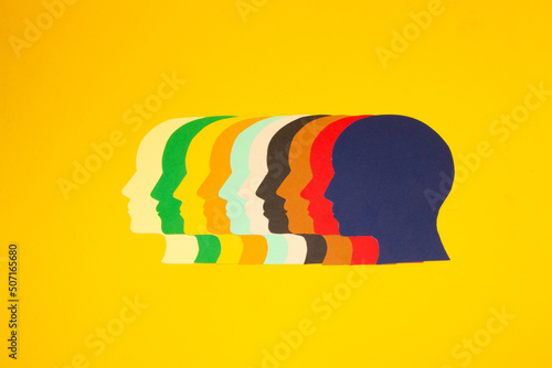 colorful paper heads looking at one point on a yellow background, all the power of the mind focused on solving problems