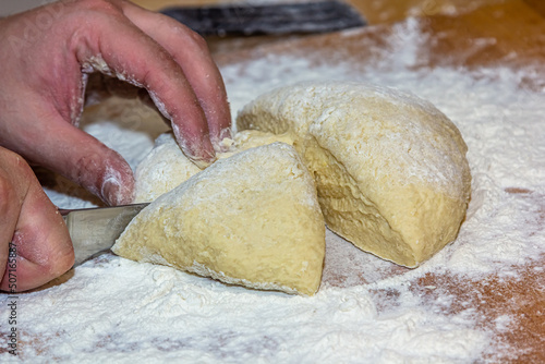 Close-up of chef hands kneading raw dough of wooden board. Baking concept