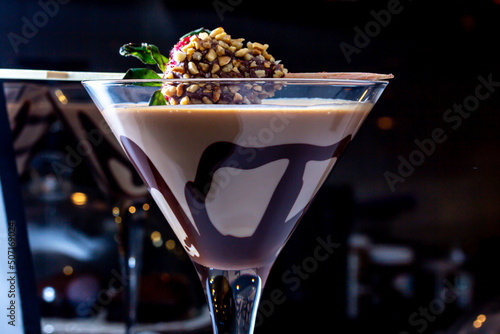 Chocolate drink with whipped cream, strawberry and pieces of black chocolate on a dark background.