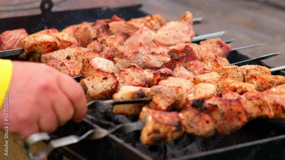 Close-up of grilling tasty dish on barbecue. Process of cooking yummy shashlik in nature. Delicious food on metal skewer in bbq. Time to picnic concept. Street food. Food festival. Pork at the stake