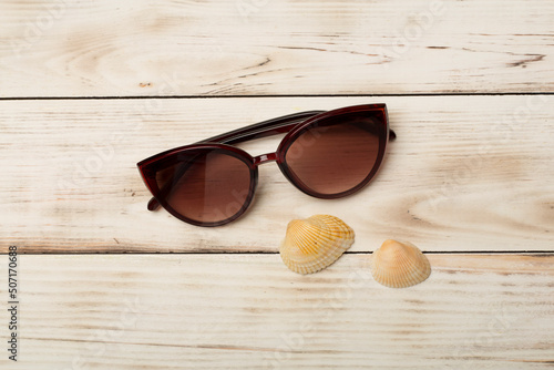 Sunglasses and seashells on color background, top view