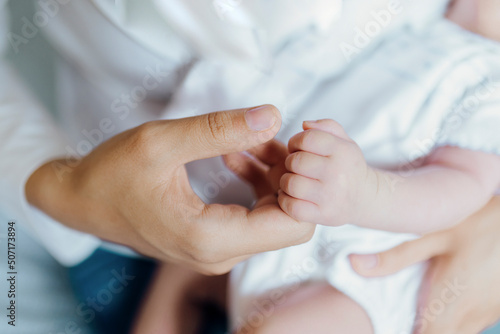 Close up mother hands holding newborn baby hand. Fingers details.