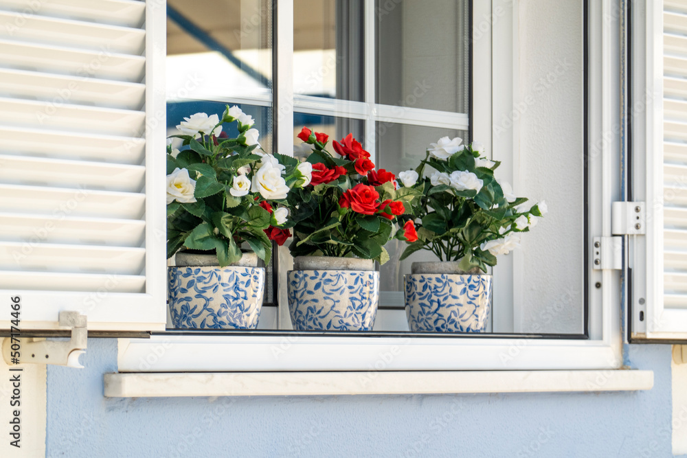 Fototapeta premium Decorative fake flower vases on a window