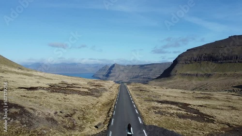 Young woman running in the middle of an scenic road at Feroe Islands photo