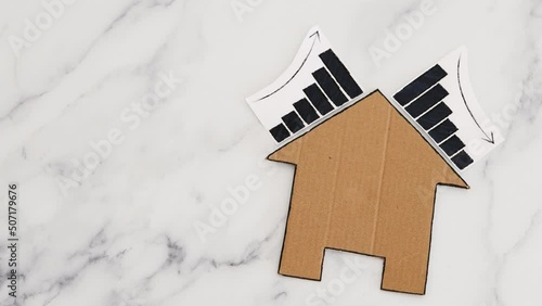 mortgages rentals and property prices increasing and decreasing, house icon made of cardboard with graph showing stats going up and down photo