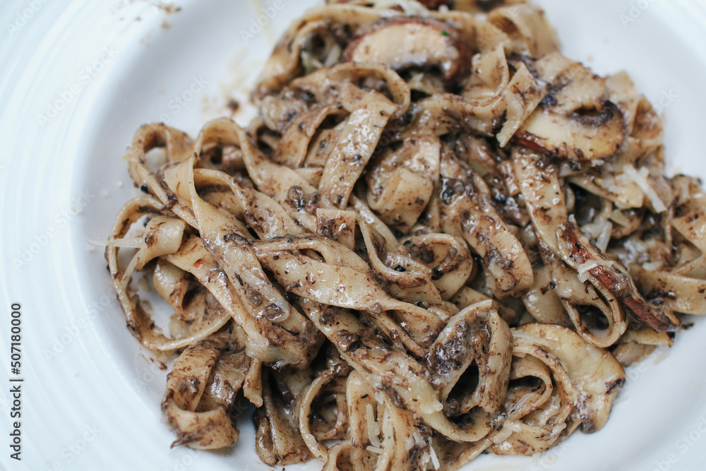 Spaghetti with truffle mushrooms and cream sauce on wooden table in restaurant. A delicious italian fusion pasta Spaghetti with truffle mushrooms and cream sauce on wooden table in restaurant. A delicious italian fusion pasta