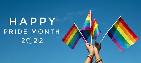'HAPPY PRiDE MONTH 2022' on bluesky and rainbow flags background, concept for lgbtq+ celebrations in pride month, june, 2022.