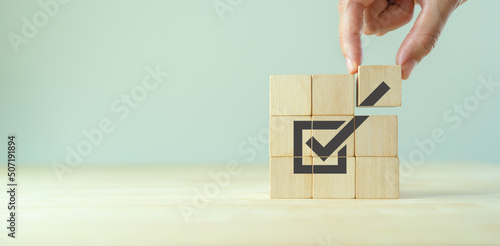Corporate regulatory and compliance. Goals achievement and business success. Task completion. Ethical corporate. Do the right thing. Quality and ISO symbol. Placing wooden cube with checkmark icon..