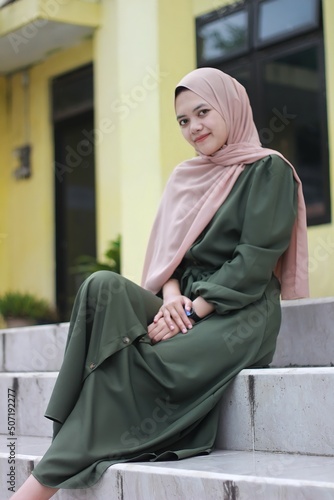 Beautiful girl sitting relaxing, Portrait of young Asian woman, wearing hijab and green clothes. photo