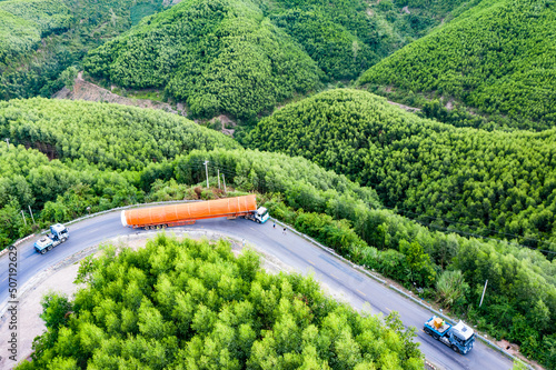 Transporting wind turbine propeller through curvy jungle road. Clean alternative energy to reduce global warming and climate change for sustainable growth.