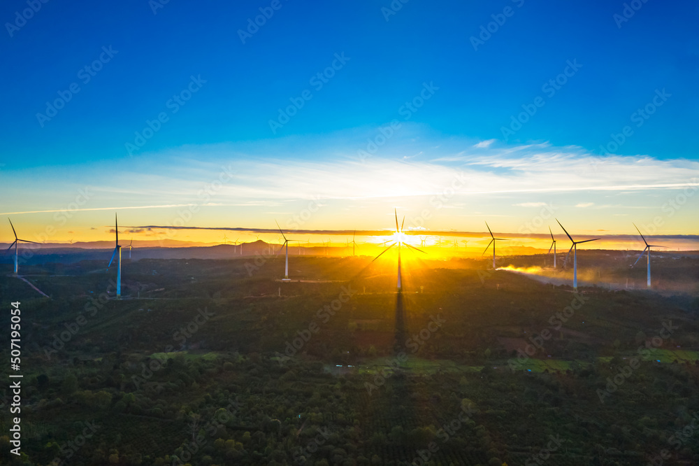 Obraz premium Wind turbine towers farm in a big field to generate electricity. Clean alternative energy concept to reduce global warming and climate change for sustainable growth.