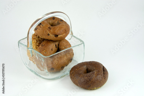 Variety of cinnamon raisin, sesame seed, and pumpernickel bagels inside glass basket photo