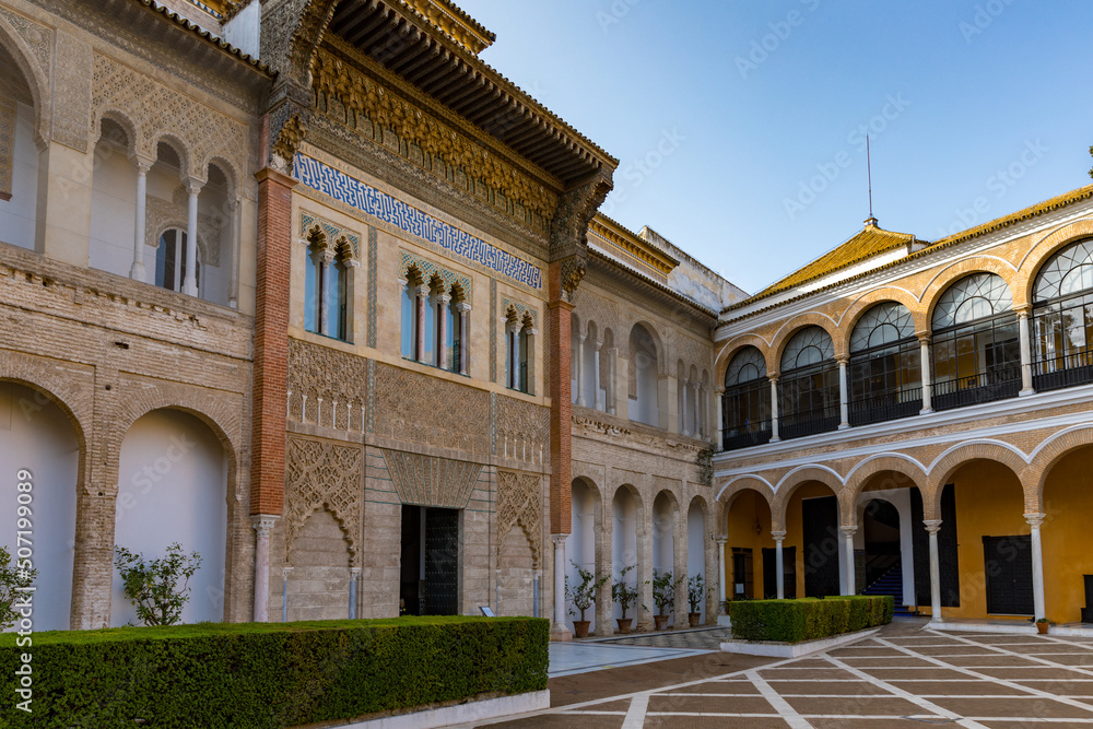 Buildings of Alcazar palace in Sevilla. With beautiful formal public garden inside Alcazar Seville palace in summertime in Andalusia