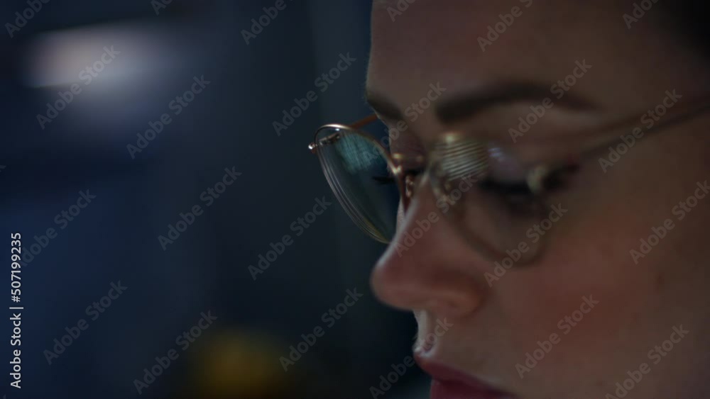 A woman computer programmer working late at night with coding reflections in her glasses A woman computer programmer working late at night with coding reflections in her glasses